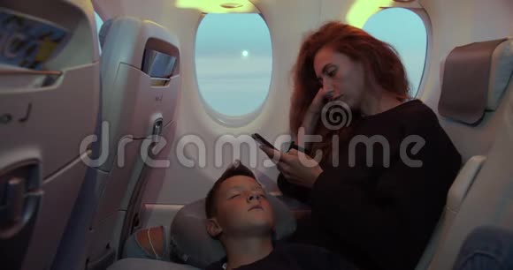男孩在飞机上飞行时靠母亲的手睡觉视频的预览图