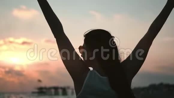 在日落时漫步在海滩上的旅行女性的后景轮廓享受自由放松视频的预览图