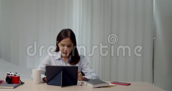 一位在家拿平板电脑工作的亚洲年轻女性视频的预览图