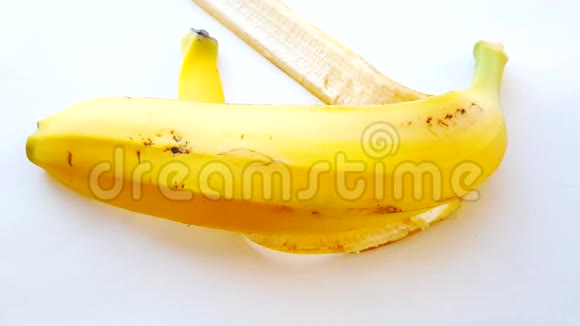 香蕉皮在白色背景上阳光明媚一个女人手把果皮放在桌子上视频的预览图