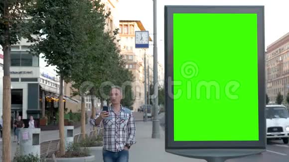 一个人正沿着城市的街道走着在绿色屏幕附近的电话亭里聊天视频的预览图