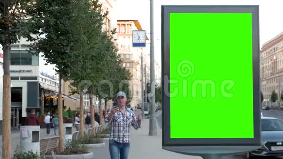 一个人正沿着城市的街道走着在绿色屏幕附近的电话亭里聊天视频的预览图
