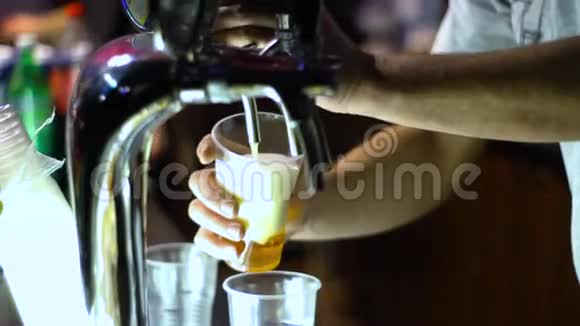 一个人用塑料杯从水龙头里抽出啤酒在黑色背景下孤立视频的预览图