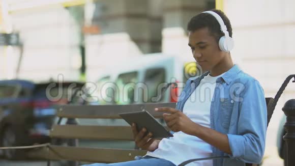 性格开朗的混血男孩带着平板电脑放下耳机微笑着对着镜头视频的预览图