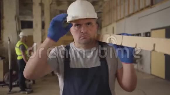 一位疲惫的白种人男性工人在施工现场用木板行走的肖像成人建设者起飞视频的预览图