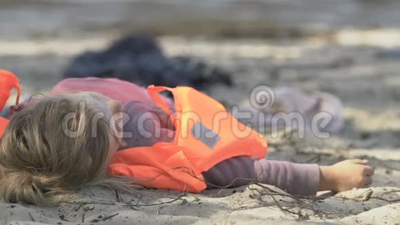 穿救生衣的女孩躺在没有意识的海岸上自然灾害的受害者视频的预览图
