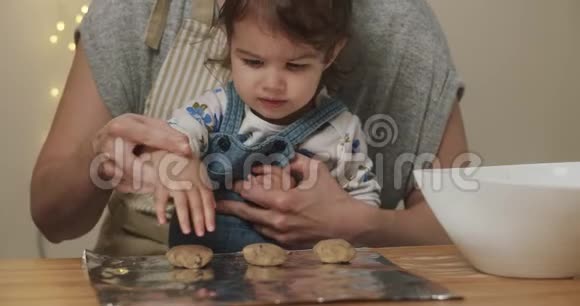 可爱的蹒跚学步的女孩帮妈妈做饼干视频的预览图