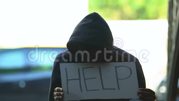 戴着帽子的黑人难民带着帮助词展示纸板需要庇护视频的预览图