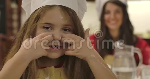 开朗的小白种人女孩的特写脸用面粉和眨眼在脸上画线年轻的微笑妈妈视频的预览图