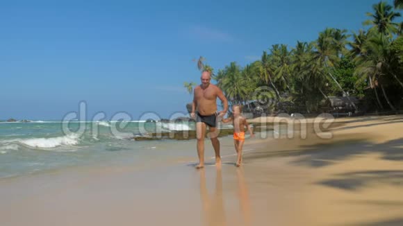 父亲和儿子一起沿着美丽的海边奔跑视频的预览图