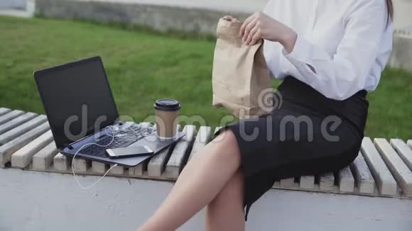 无法辨认的商务女性在公园里吃羊角面包和喝咖啡视频的预览图