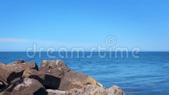 年轻的旅游旅行者欣赏海景坐在海边的巨大鹅卵石上视频的预览图