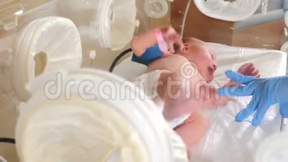 早产婴儿在孵化器里婴儿足在重症监护医院病床后出生新生儿1天产房视频的预览图