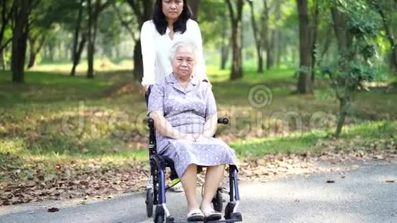 亚洲老年或老年妇女在公园度假时在轮椅上得到照顾帮助和支持健康强壮的医疗视频的预览图