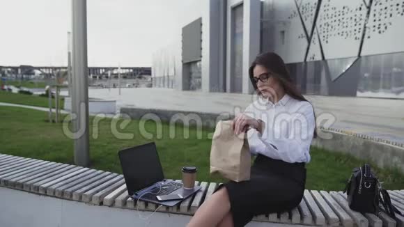 成功的商务女性在午餐时间在户外吃牛角面包和喝咖啡视频的预览图