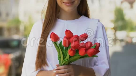 微笑的年轻女子手捧红色郁金香国际妇女节庆典视频的预览图