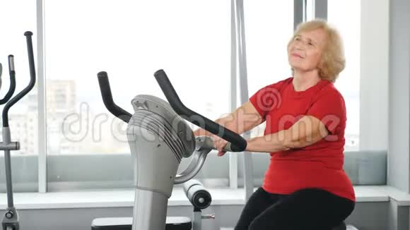 健身俱乐部活跃的老妇人骑着运动自行车进行有氧训练的肖像健康活跃的老年妇女视频的预览图