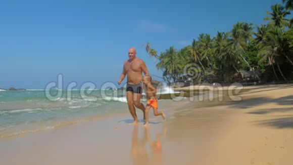 快乐的男孩和父亲花时间在空荡荡的海滩上奔跑视频的预览图