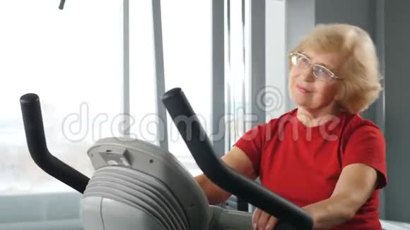 健身房里活跃的高级女性健身室骑自行车的女运动员骑自行车的老女人视频的预览图