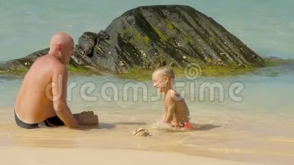 有趣的爸爸在热带度假村把湿沙扔给儿子视频的预览图