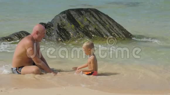 父子一家人在海滩上的清澈海水中休息视频的预览图