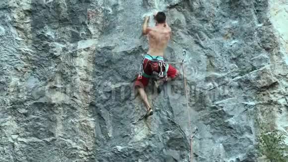 年轻强壮的攀岩者小心翼翼地爬上悬崖寻找伸手和抓住视频的预览图