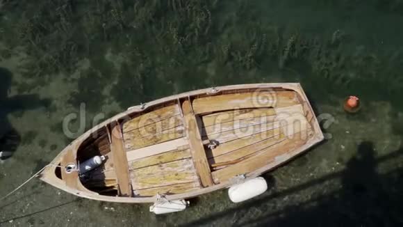 一艘没有人的木船在阳光下漂浮在清澈的水中视频的预览图