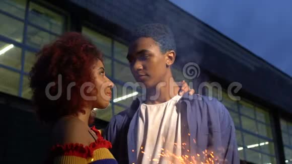 混合种族的青少年拥抱在户外明亮的火花消遣慢动作视频的预览图