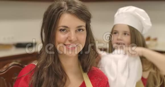 一幅美丽的高加索女人的特写肖像看着相机微笑着幼儿园的小女孩戴着厨师帽视频的预览图
