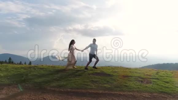 山地探险穿着白色长裙的男人和女人在阳光下跑过小山4k视频的预览图