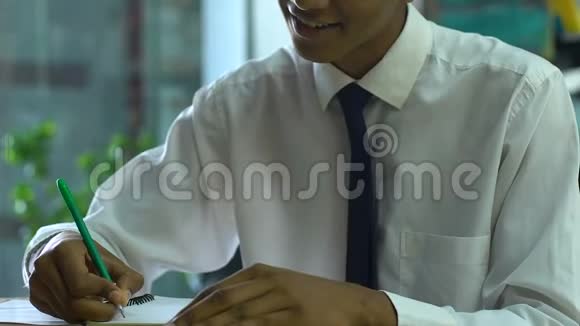 男同学在笔记本上微笑着对着镜头写作入学考试成功视频的预览图