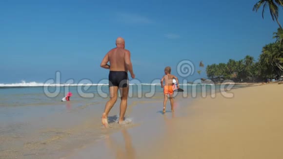 父亲和儿子用手掌沿着海滨海滩奔跑视频的预览图