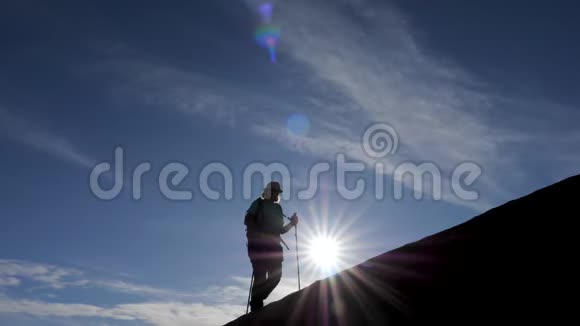 一位背包旅客登上日落山背景的游客剪影视频的预览图