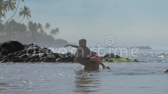 有趣的男孩爬上爸爸的肩膀在岩石上跳海视频的预览图