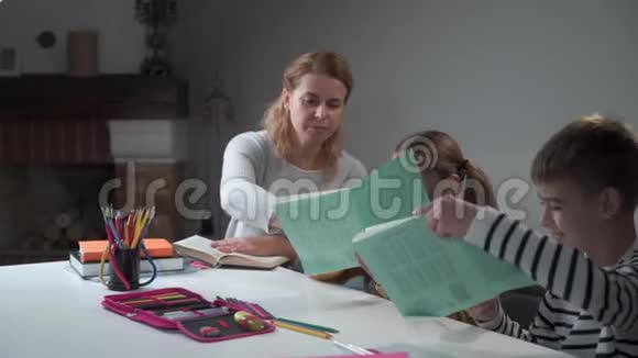 善良的白人母亲在家教孩子微笑的男孩和女孩和妈妈一起做作业孩子们在运动中写作视频的预览图