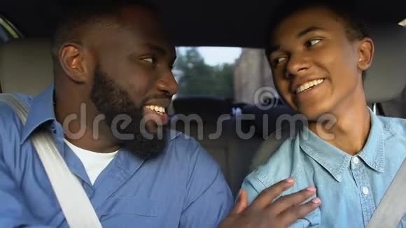 快乐的美国黑人男子在驾驶座上鼓励微笑的青少年成就视频的预览图