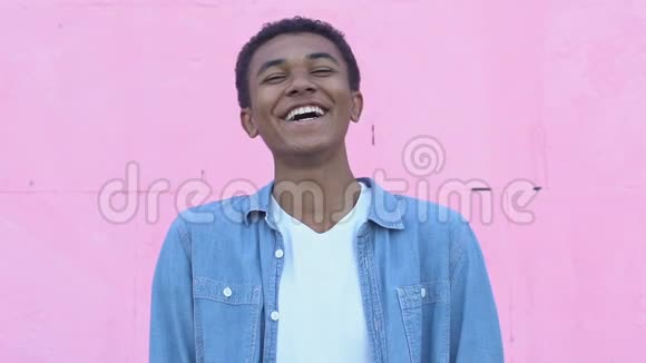 快乐的美国黑人男孩在粉红色的背景下笑享受无忧无虑的青春视频的预览图
