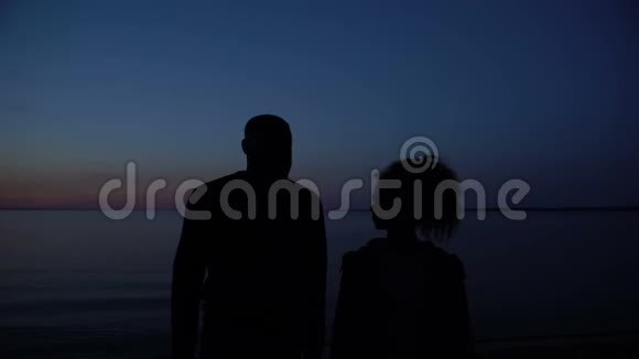 幸福的夫妻拥抱在夜海背景下的剪影视频的预览图