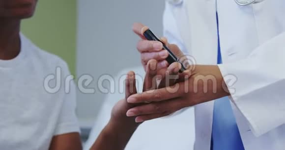 非裔美国女医生在医院病房检查男性患者血糖水平的特写视频的预览图