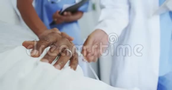 非裔美国女医生在病房里将静脉滴注于男性病人手上的正面观察视频的预览图