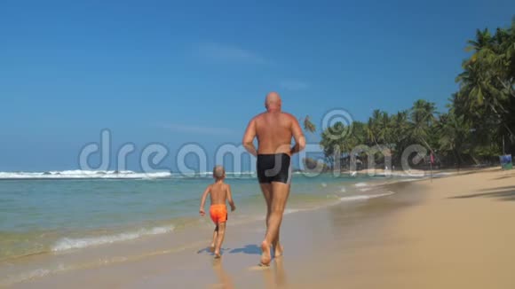 一家人带着爸爸和儿子沿着海边慢动作跑视频的预览图