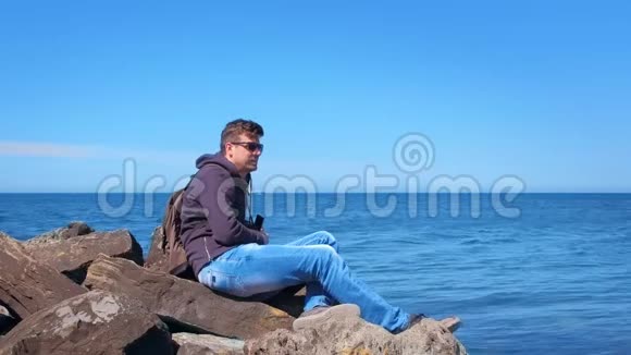 观光客欣赏海景坐在海边的巨大鹅卵石视频的预览图