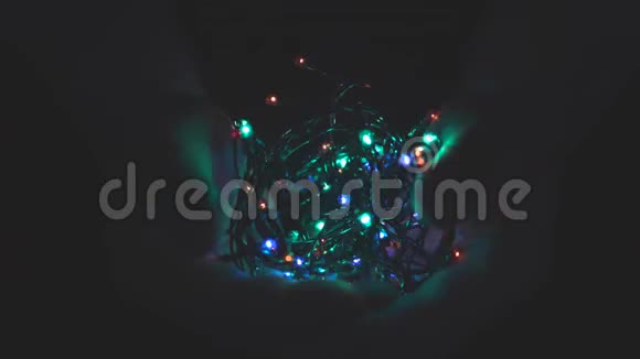 在黑暗的背景下用男性手中的灯光燃烧着节日的圣诞花环选择性聚焦模糊复古色调视频的预览图