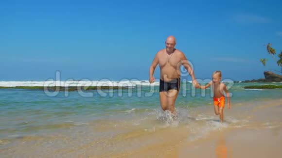 爸爸牵着小男孩的手在海边奔跑视频的预览图