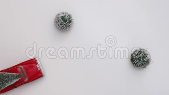 红色的微型玩具车在白色的雪地背景上载着一棵圣诞树上景复制空间慢动作概念视频的预览图