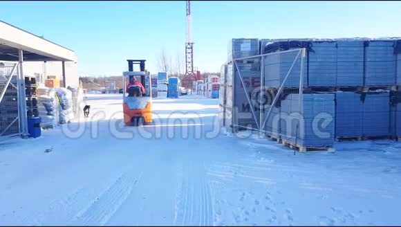 电动叉车在一个开放的仓库区移动过去的建筑材料堆放在冬季寒冷现代仓库系统4Kvi视频的预览图