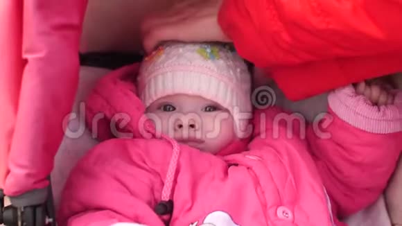 小孩子躺在婴儿车里穿着夹克和帽子在秋天和他的母亲一起散步春天在公园里视频的预览图