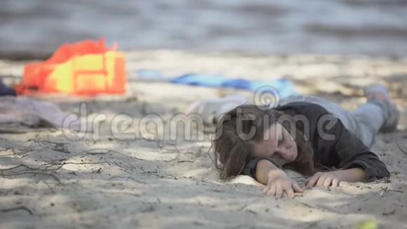 女人喘着粗气在海难之后躺在海滩上请求帮助视频的预览图