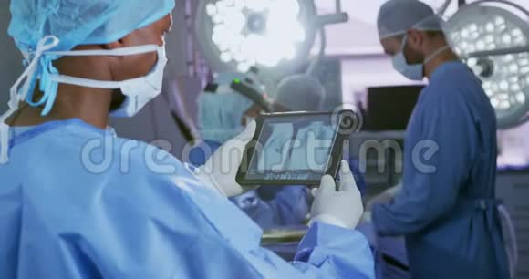 在一家医院的手术室中使用数字平板电脑对非裔美国男性外科医生进行特写视频的预览图