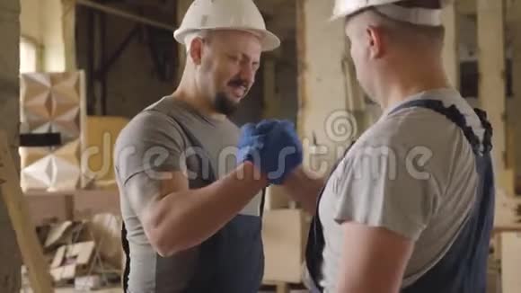 两个高加索建筑工人握手微笑两人在施工现场工作白人同事视频的预览图